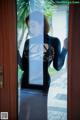 A woman in a black dress standing in front of a door.