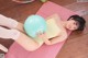 A woman laying on a yoga mat holding a blue ball.