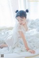 A woman in a white dress sitting in a bathtub filled with foam.