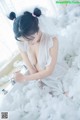 A woman in a white dress sitting in a bathtub covered in foam.