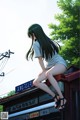 A woman sitting on top of a building next to a street sign.