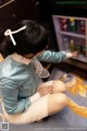 A woman sitting on the floor in front of a refrigerator.