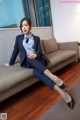 A woman in a suit sitting on a couch.