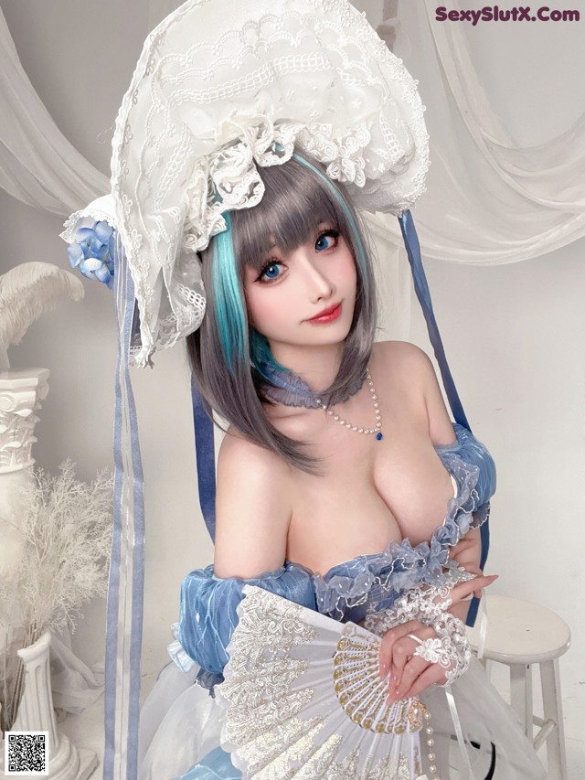 A woman in a blue and white dress holding a fan.