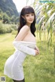 A woman in a white dress posing in a field.