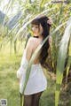 A woman in a white dress standing in a field of tall grass.