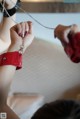 A woman in a red dress is holding a chain around her wrist.