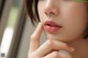 a close up of a woman's face with her hand on her chin