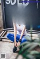 A woman sitting on the ground in front of a blackboard.