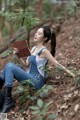 A woman sitting in the woods reading a book.