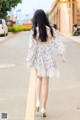 A woman walking down the street in a white dress.