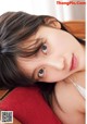 A young woman laying on top of a red pillow.