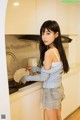 A young woman standing in a kitchen next to a sink.