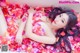 A woman laying in a bathtub covered in rose petals.