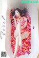 A woman laying in a bathtub covered in rose petals.